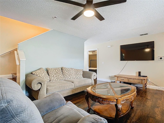 living room featuring ceiling fan, dark wood-type flooring, and a textured ceiling