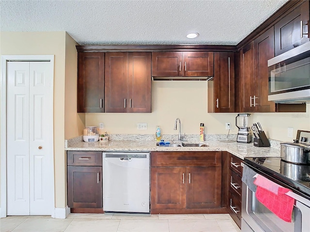 kitchen featuring a textured ceiling, appliances with stainless steel finishes, sink, light stone counters, and light tile patterned floors