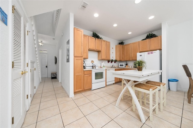 kitchen featuring light brown cabinetry, light tile patterned floors, white appliances, and sink