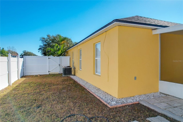 view of side of home with a yard and central AC