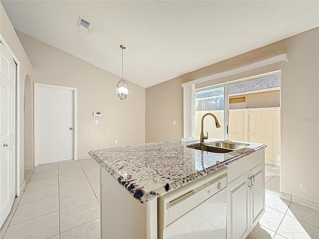 kitchen featuring light stone countertops, white dishwasher, vaulted ceiling, sink, and an island with sink