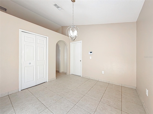 spare room with light tile patterned floors, vaulted ceiling, and a notable chandelier