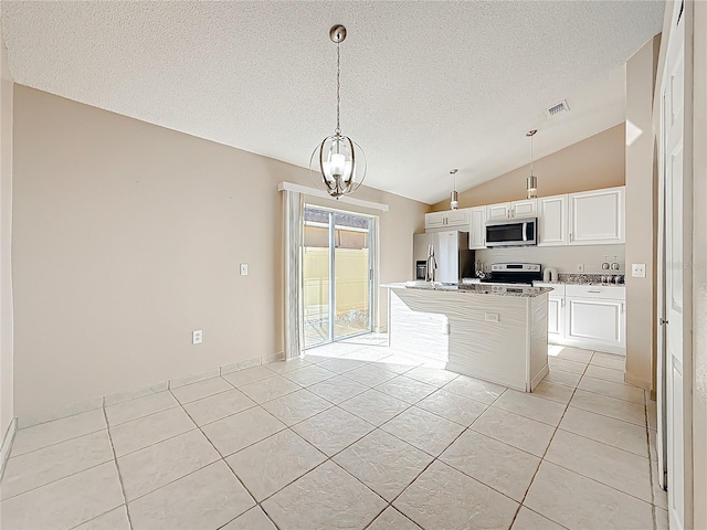 kitchen with light tile patterned floors, stainless steel appliances, vaulted ceiling, and a kitchen island with sink