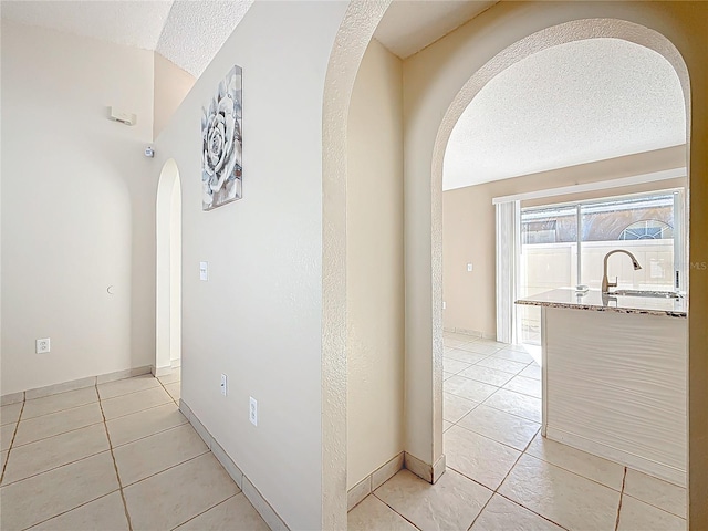 hall with light tile patterned floors and a textured ceiling