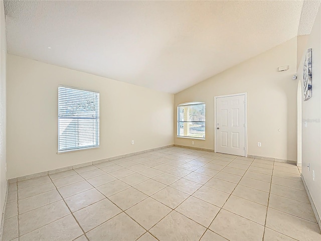 spare room featuring light tile patterned flooring, a textured ceiling, and vaulted ceiling