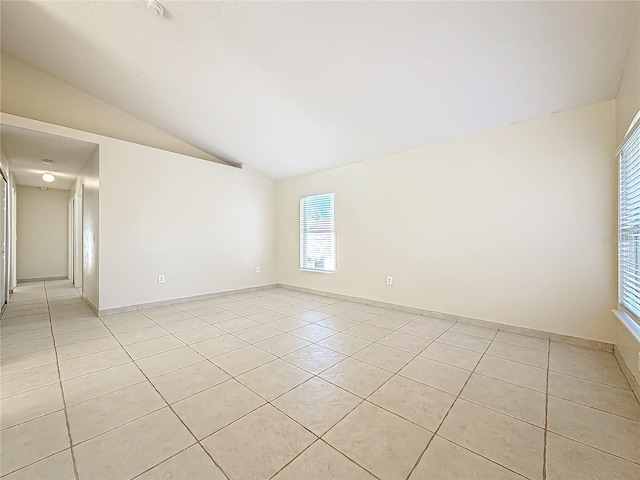 unfurnished room with lofted ceiling and light tile patterned floors