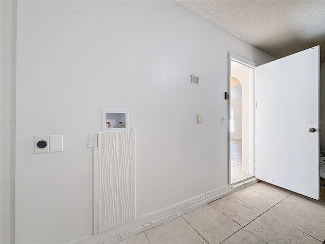 laundry room featuring light tile patterned floors, a textured ceiling, and hookup for a washing machine