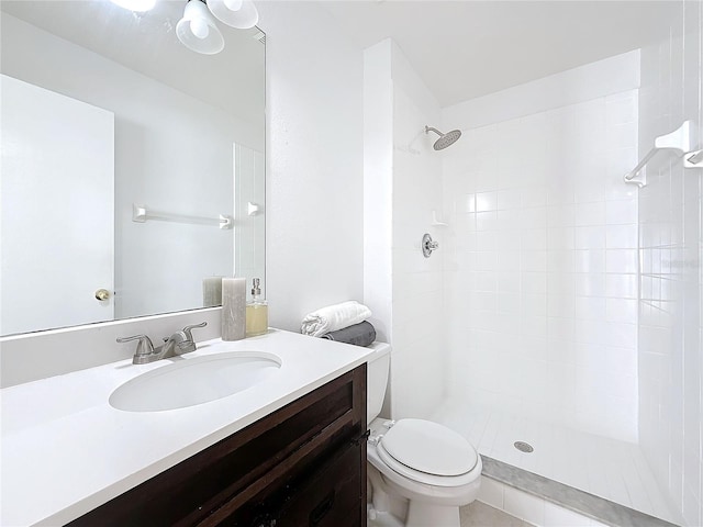 bathroom with vanity, toilet, and tiled shower