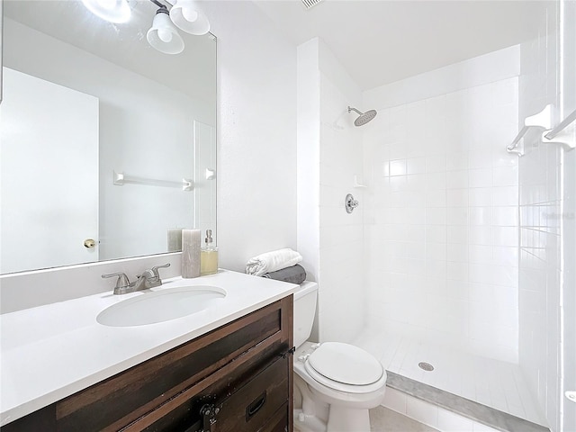 bathroom with vanity, toilet, and tiled shower