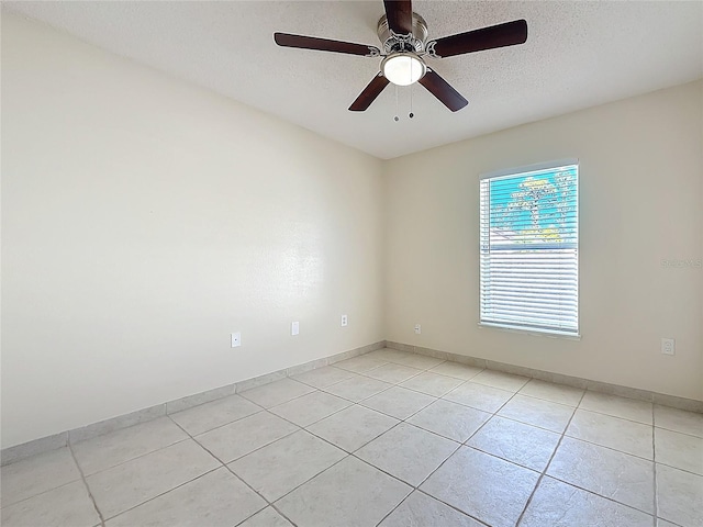 spare room with ceiling fan, light tile patterned flooring, and a textured ceiling