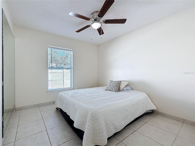 tiled bedroom featuring ceiling fan and a textured ceiling