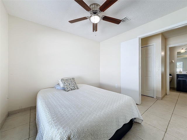 bedroom with ceiling fan, light tile patterned floors, and a textured ceiling