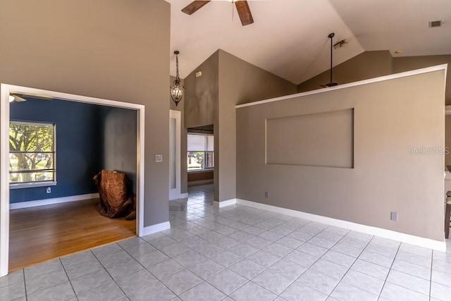 tiled spare room featuring ceiling fan with notable chandelier and lofted ceiling