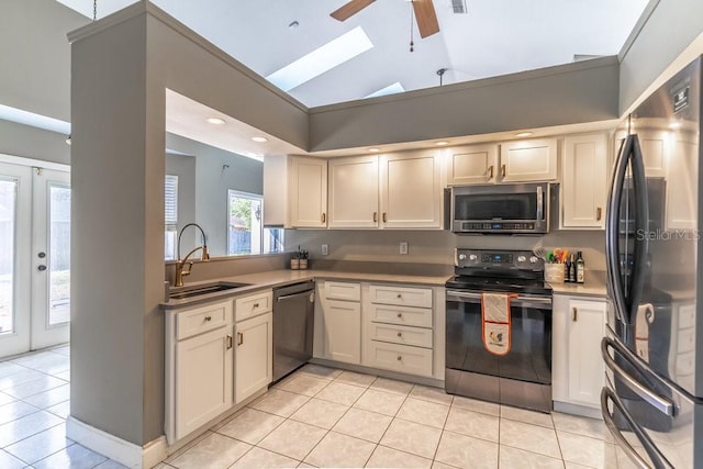 kitchen with lofted ceiling, french doors, sink, light tile patterned floors, and stainless steel appliances