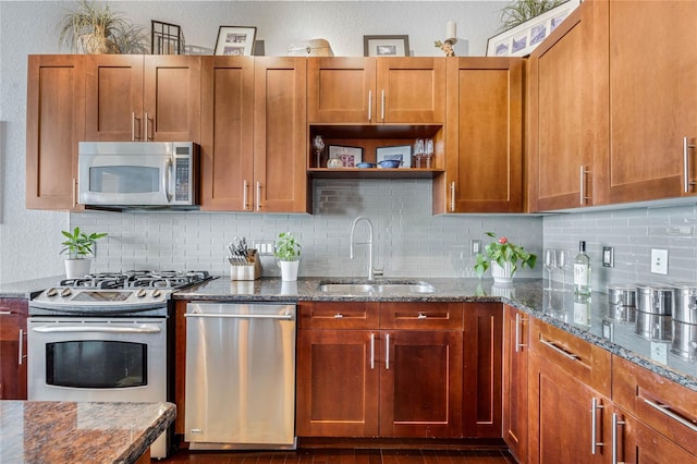 kitchen with backsplash, sink, appliances with stainless steel finishes, and dark stone counters