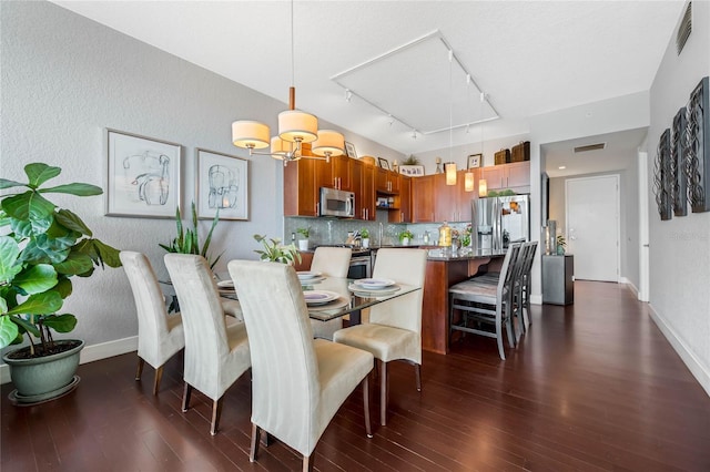 dining room with a chandelier, dark wood-type flooring, and track lighting