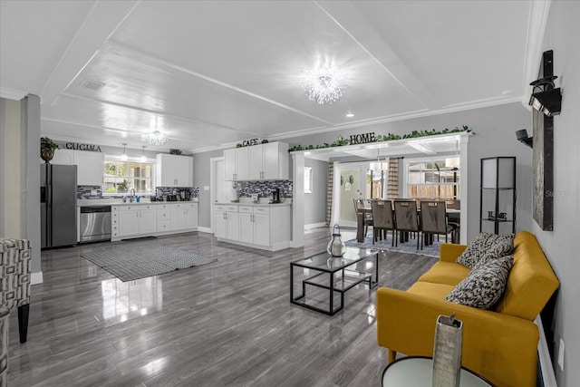 living room featuring sink, crown molding, a chandelier, and hardwood / wood-style flooring