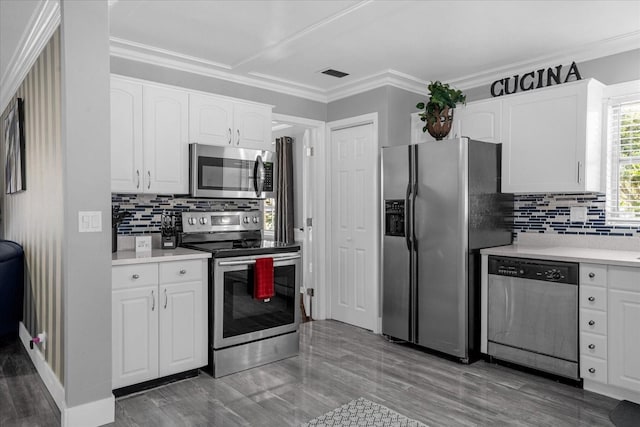 kitchen with ornamental molding, appliances with stainless steel finishes, and white cabinets