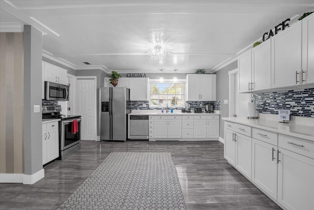 kitchen with appliances with stainless steel finishes, white cabinets, a chandelier, decorative backsplash, and crown molding