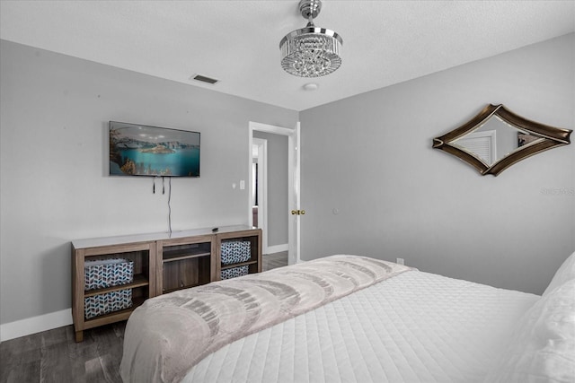 bedroom featuring a textured ceiling and dark hardwood / wood-style flooring