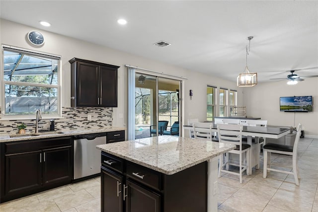 kitchen with sink, dishwasher, decorative backsplash, hanging light fixtures, and a kitchen island