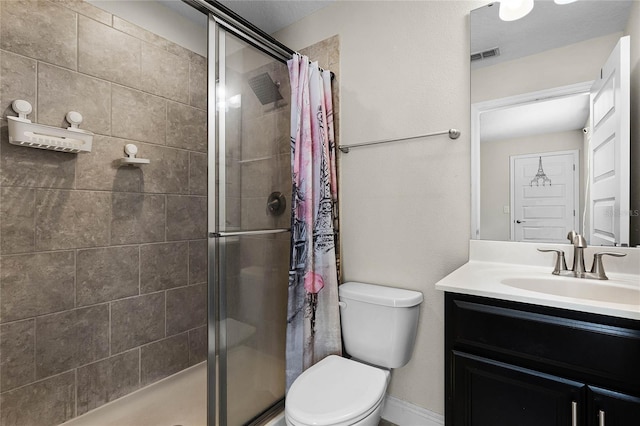 bathroom featuring toilet, tiled shower, and vanity