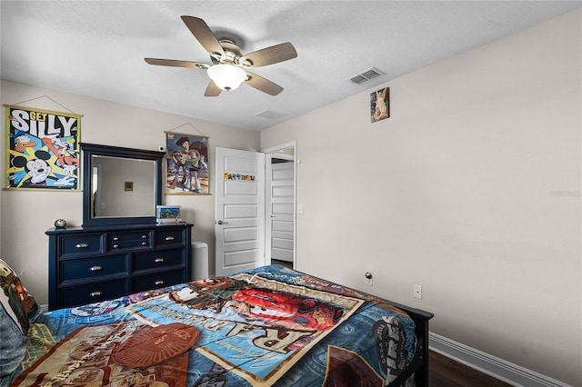 bedroom featuring dark hardwood / wood-style flooring, a textured ceiling, and ceiling fan