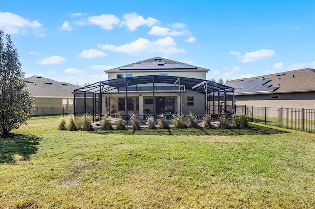 back of house featuring a lawn, a lanai, and solar panels