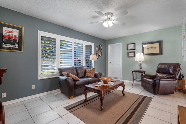 living area with ceiling fan, a textured ceiling, baseboards, and light tile patterned floors