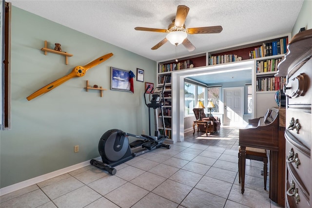 workout room featuring tile patterned flooring, ceiling fan, and a textured ceiling