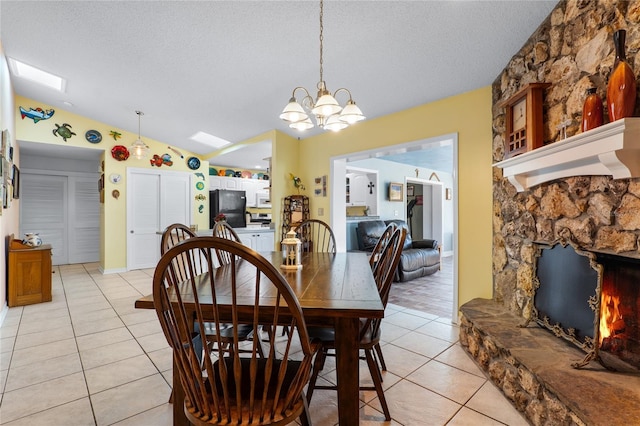 dining room with lofted ceiling, an inviting chandelier, a textured ceiling, a fireplace, and light tile patterned flooring