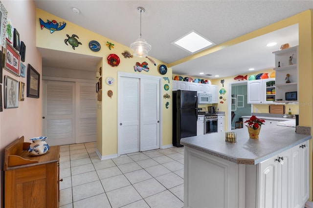 kitchen featuring stainless steel gas stove, white cabinets, white microwave, freestanding refrigerator, and open shelves