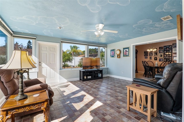 living area with visible vents, baseboards, and ceiling fan with notable chandelier