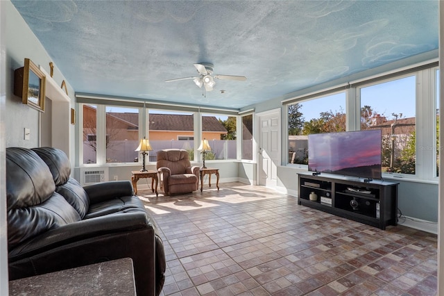 living area featuring ceiling fan, baseboards, and a textured ceiling