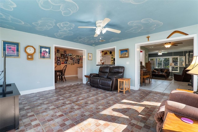 tiled living room featuring a ceiling fan and baseboards