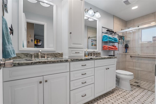 bathroom with double vanity, visible vents, toilet, a sink, and a shower stall