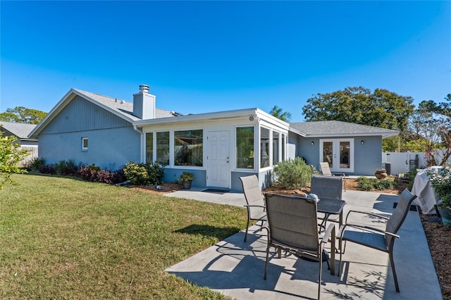 rear view of property featuring a lawn, a chimney, fence, french doors, and a patio area