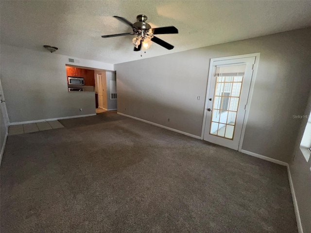 unfurnished living room with ceiling fan, dark carpet, and a textured ceiling