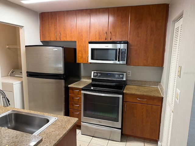 11538 Westwood Blvd Unit 226, Orlando, FL 32821 - kitchen with stainless steel appliances, washer / dryer, light tile patterned flooring, light countertops, and brown cabinets