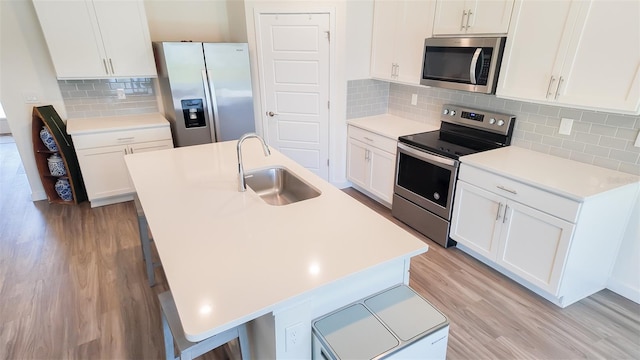 kitchen with white cabinetry, sink, stainless steel appliances, and a center island with sink