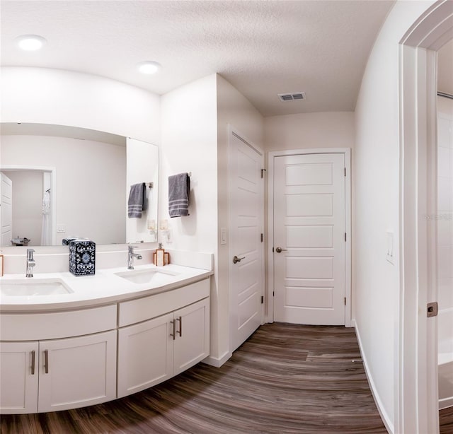 bathroom featuring vanity, hardwood / wood-style flooring, and a textured ceiling