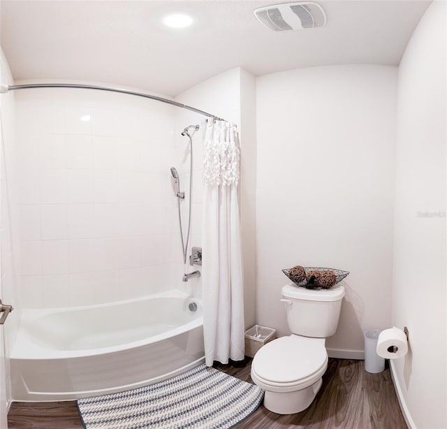 bathroom featuring hardwood / wood-style flooring, shower / bath combo with shower curtain, and toilet