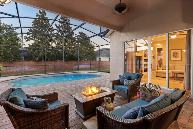 pool at dusk with glass enclosure, an outdoor living space with a fire pit, and a patio area