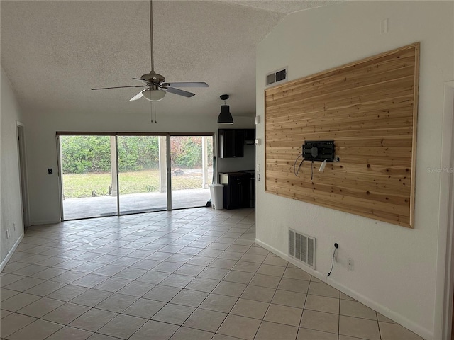 tiled spare room featuring ceiling fan, a textured ceiling, and vaulted ceiling