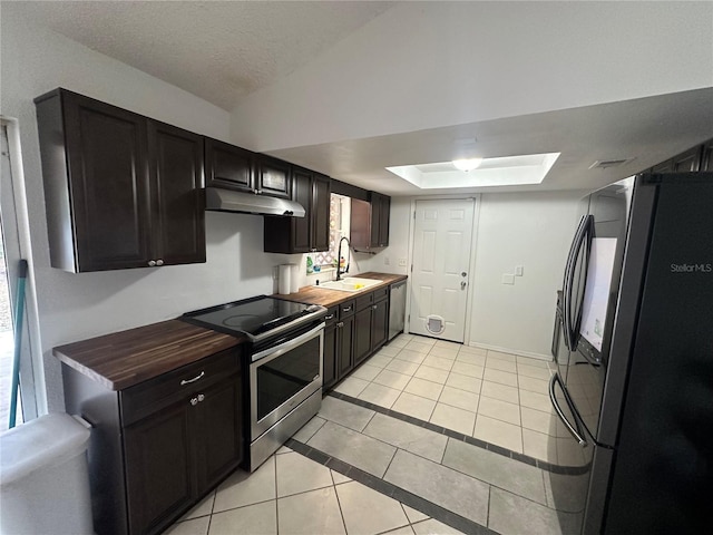 kitchen with sink, stainless steel appliances, wood counters, a textured ceiling, and light tile patterned flooring