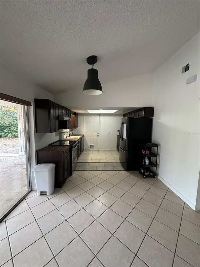 kitchen featuring dark brown cabinets, light tile patterned floors, and a textured ceiling