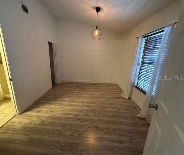 corridor with hardwood / wood-style floors, a textured ceiling, and vaulted ceiling