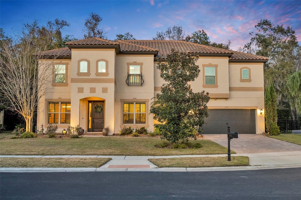 124 Adler Pt, Oviedo, FL 32765 - mediterranean / spanish-style home with an attached garage, a lawn, a tile roof, stucco siding, and driveway