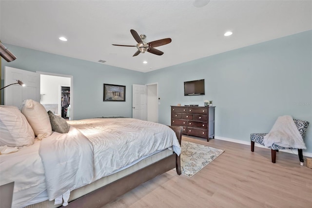 bedroom featuring ceiling fan, a walk in closet, light hardwood / wood-style floors, and a closet