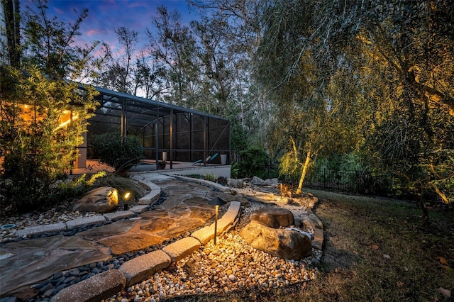 yard at dusk featuring a lanai